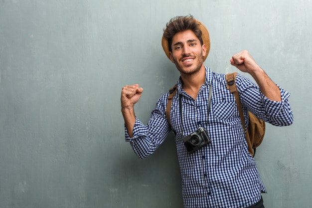 Jonge knappe reiziger man met een strooien hoed, een rugzak en een fotocamera erg blij