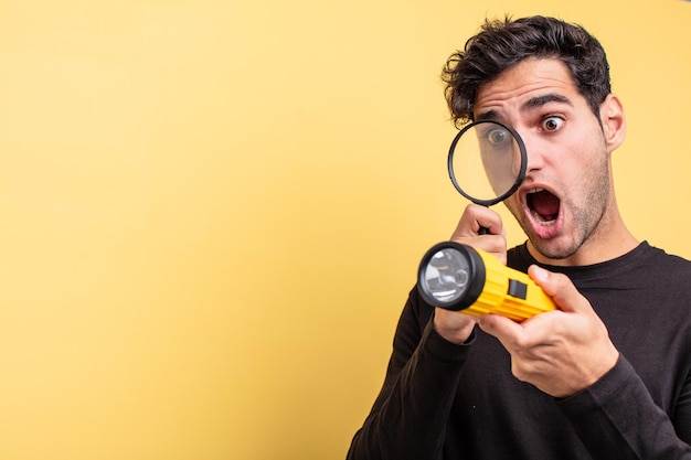 Jonge knappe Spaanse man met een vergrootglas en een lantaarn