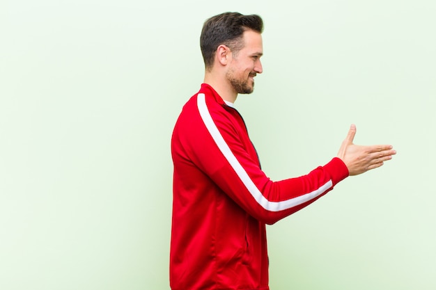 Jonge knappe sportmens die glimlachen, u begroeten en een handschok aanbieden om een succesvolle overeenkomst te sluiten