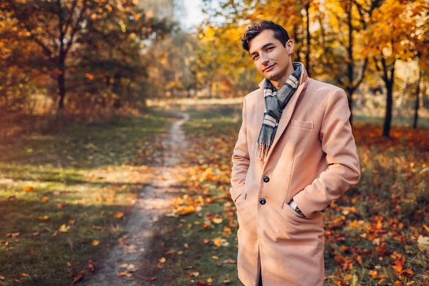 Jonge knappe zakenman die klassieke kleding en accessoires in de herfstbos draagt bij zonsondergang