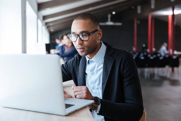 Jonge knappe zakenman die met laptop op kantoor werkt