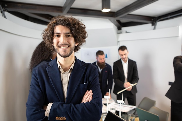 Jonge knappe zakenman glimlachend in een kantoor met collega's