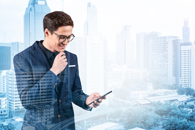 Jonge knappe zakenman in pak en bril die telefoon gebruikt en nadenkt over hoe het probleem aan te pakken nieuwe carrièremogelijkheden MBA Kuala Lumpur op achtergrond Dubbele belichting