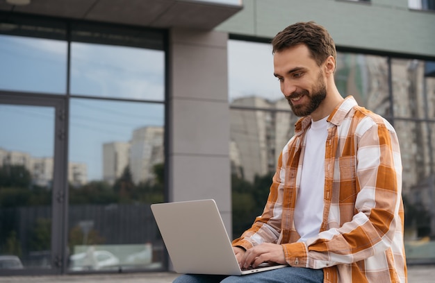 Jonge knappe zakenman laptopcomputer gebruikt, typen, online werken