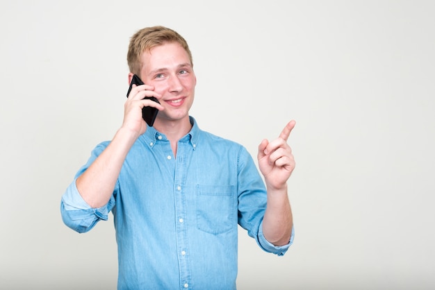 jonge knappe zakenman met blond haar tegen witte muur