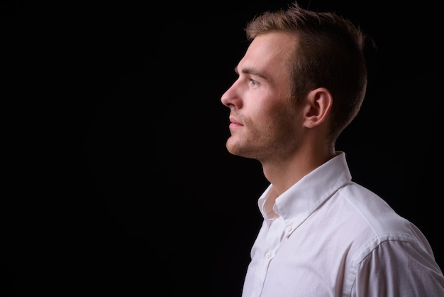 jonge knappe zakenman met blond haar tegen zwarte muur