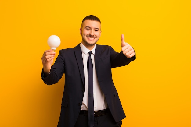 Jonge knappe zakenman tegen vlakke muur met een gloeilamp