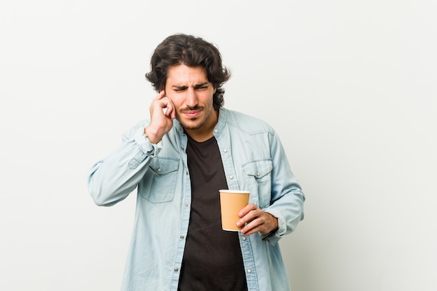 Jonge koele mens die een koffie drinkt die oren behandelt met handen.