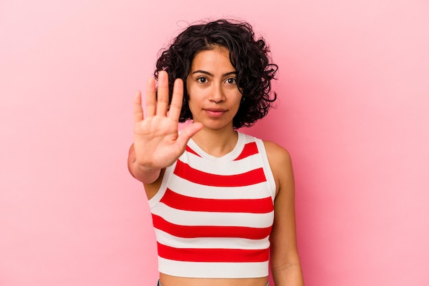 Jonge krullende Latijnse vrouw die op roze vrolijk glimlachen als achtergrond wordt geïsoleerd die nummer vijf met vingers toont.