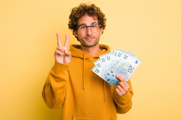 Jonge, krullende, slimme man met eurobankbiljetten op een gele achtergrond