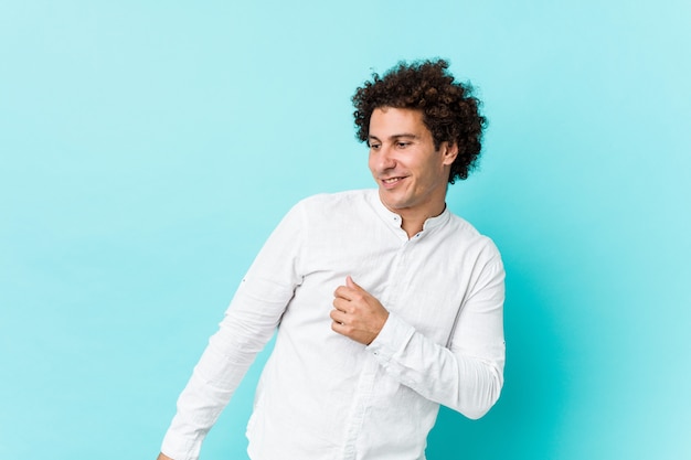 Jonge krullende volwassen man draagt een elegant shirt dansen en plezier maken.