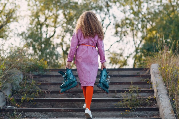 Jonge krullende vrouw die rolschaatsen gaat in het park.