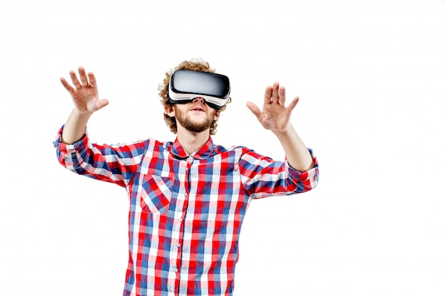 Jonge krullendharige man in plaid shirt met behulp van een VR-headset en exp