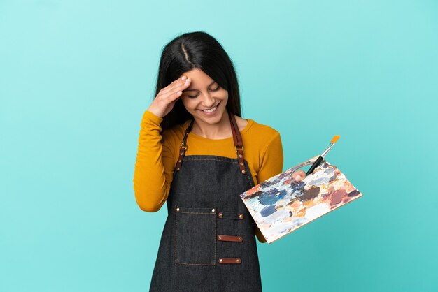 Jonge kunstenaar blanke vrouw met een palet geïsoleerd op blauwe achtergrond lachen