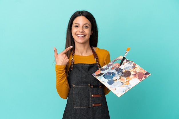 Jonge kunstenaar blanke vrouw met een palet geïsoleerd op een blauwe achtergrond met een duim omhoog gebaar