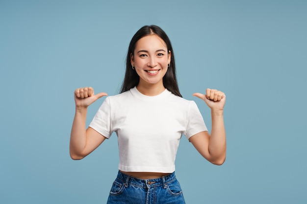 Jonge lachende Aziatische vrouw wijst met de duim naar zichzelf mock-up kopie ruimte