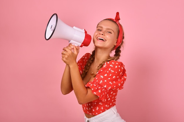 Jonge lachende blanke vrouw in vrijetijdskleding houdt megafoonstandaards in de studio