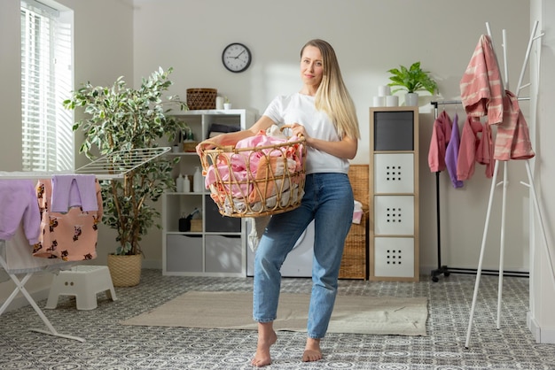 Jonge lachende blonde vrouw brengt tijd thuis door met huishoudelijk werk, midden in de wasruimte