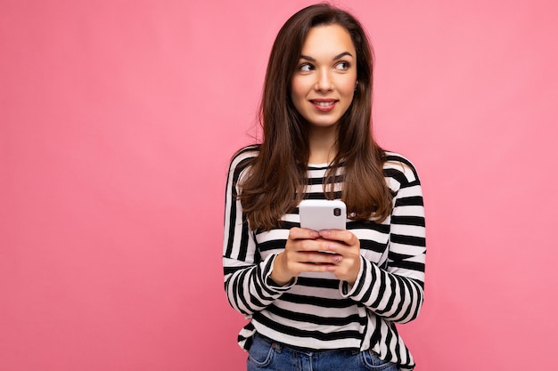 jonge lachende brunette vrouw met behulp van mobiele telefoon communiceren via sms-berichten