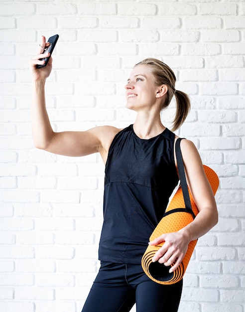 Jonge lachende fitness vrouw selfie na training