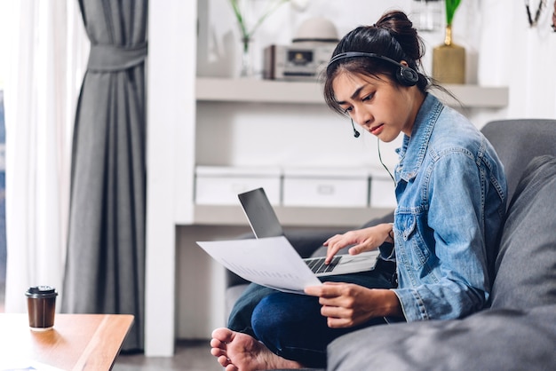 Jonge lachende gelukkig mooie Aziatische vrouw ontspannen met behulp van laptop computer werken en videoconferentievergadering thuis.