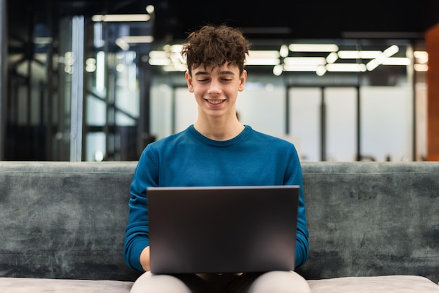 Jonge lachende man aan het werk met een laptop in een kantoor