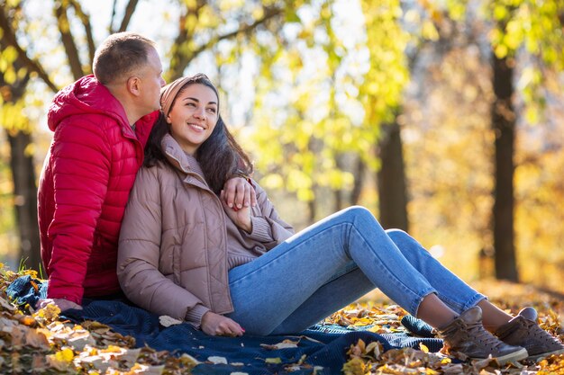 Jonge lachende man en vrouw knuffelen in het herfstpark. romantisch paar op een date. liefde en tederheid in een relatie. detailopname.