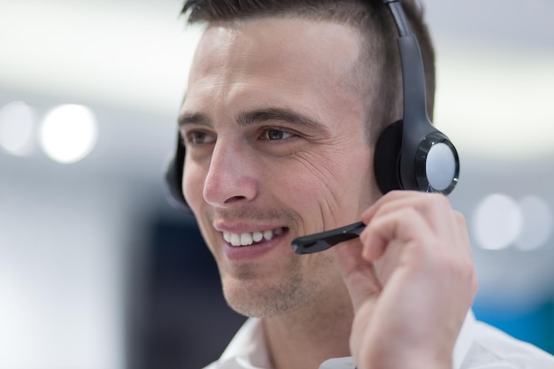 jonge lachende mannelijke callcentermedewerker doet zijn werk met een headset