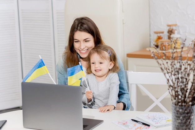 Jonge lachende moeder werkt thuis met haar schattige baby Werk thuis het meisje communiceert Oekraïne