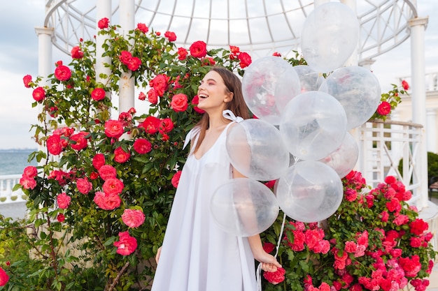 Jonge lachende mooie vrouw met ballonnen buitenshuis over bloemen