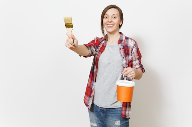 Jonge lachende mooie vrouw met verfemmer en aanwijspende borstel op kopie ruimte geïsoleerd op een witte achtergrond. Instrumenten, accessoires, gereedschappen voor renovatie appartement kamer. Reparatie huis concept.