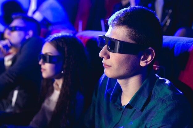 Jonge lachende vrienden in 3d-bril die popcorn eten en film kijken in de bioscoop