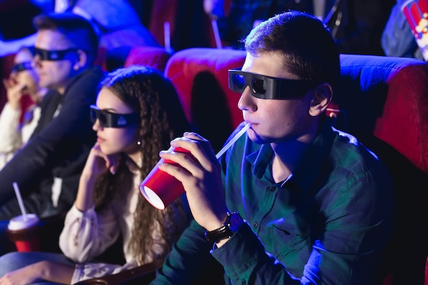 Jonge lachende vrienden in 3D-bril eten popcorn en kijken naar film in de bioscoop