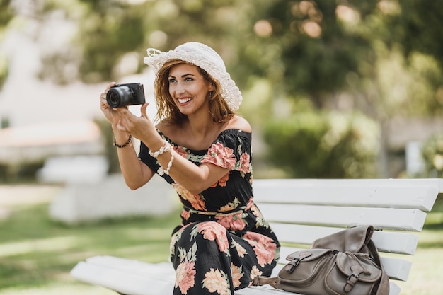 Jonge lachende vrouw die foto's maakt met haar digitale camera terwijl ze geniet van een zomervakantie.