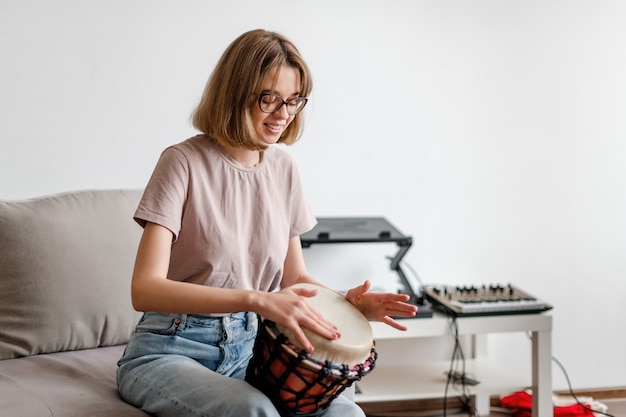 Jonge lachende vrouw djembe drum thuis spelen