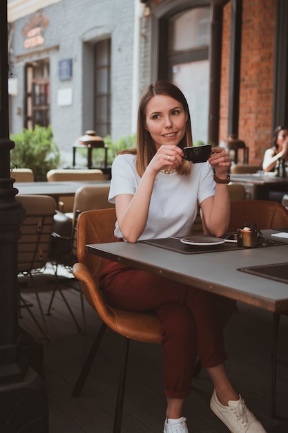 Jonge lachende vrouw drinkt koffie in een straatcafé