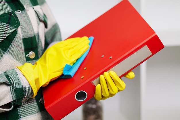 Foto jonge lachende vrouw in gele handschoenen die het huis schoonmaakt