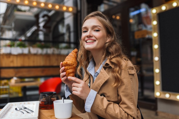 Jonge lachende vrouw in trenchcoat gelukkig