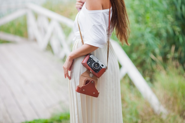 Jonge lachende vrouw in vintage stijl kleding met retro camera