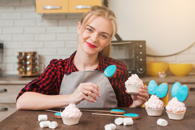 Jonge lachende vrouw koken zelfgemaakte cup cakes in de keuken