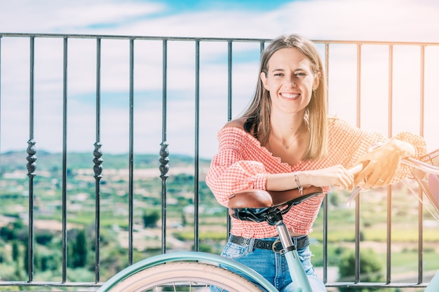 Jonge lachende vrouw met fiets rust zittend met prachtig landschap