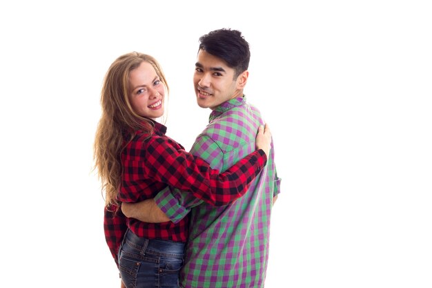 Jonge lachende vrouw met jonge knappe man met donker haar in geruite overhemden knuffelen