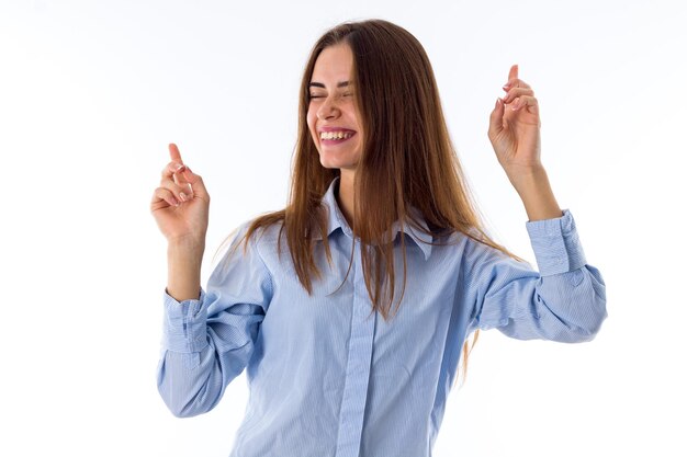 Jonge lachende vrouw met lang haar in blauw shirt dansen op een witte achtergrond in studio