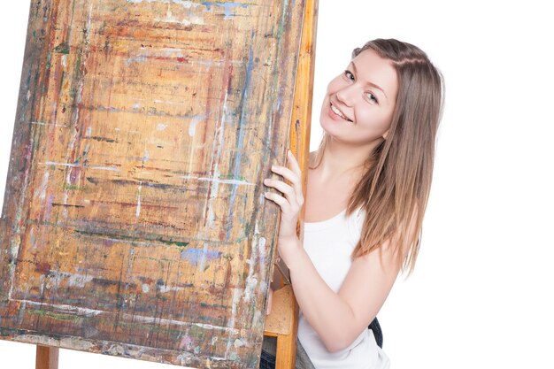 Jonge lachende vrouw schilder verstopt achter ezel