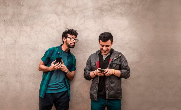 Jonge Latijns-man bespioneert een andere mobiele telefoon, man toont zijn mobiele telefoon aan een andere man