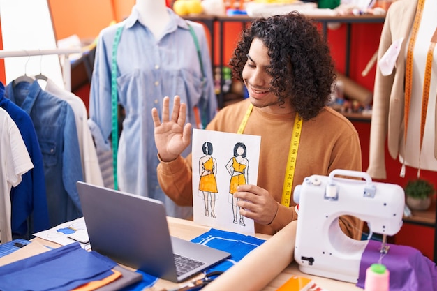 Jonge latijns-man kleermaker met videogesprek met kledingontwerp in atelier