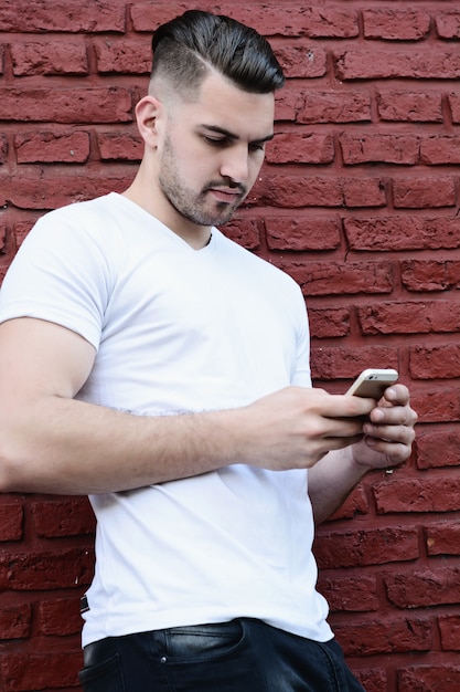 Jonge latijns-man typen op zijn telefoon