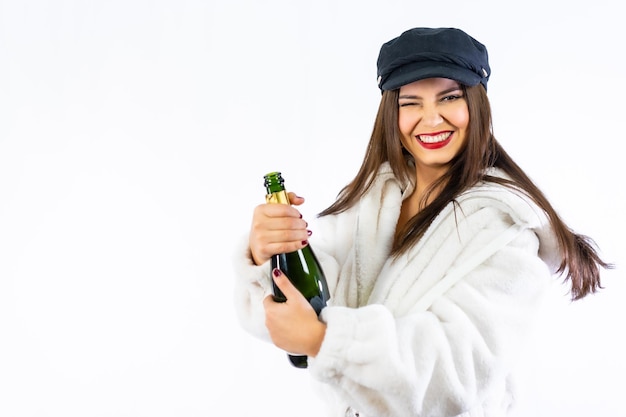 Jonge Latijns-meisje viert oudejaarsavond op een witte achtergrond. Heel glimlachend een fles champagne openen