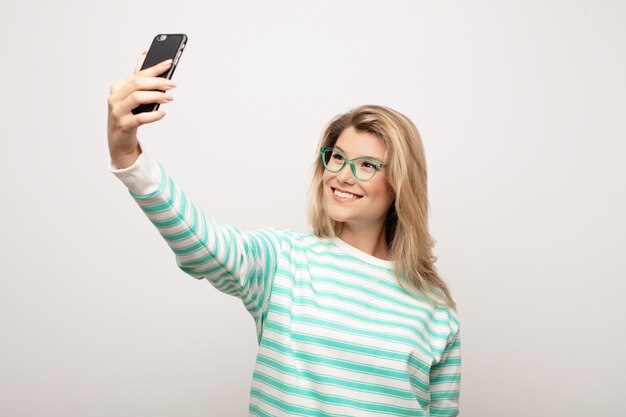 Jonge Latijns-mooie vrouw tegen vlakke muur met een slimme telefoon