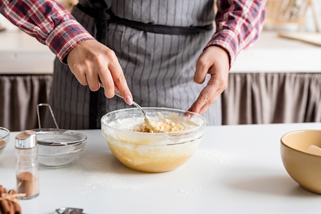 Jonge Latijns-vrouw die deeg het koken bij de keuken mengt